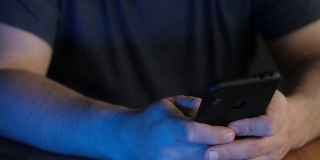 一个男人的手在霓虹灯下拨打手机号码的特写。