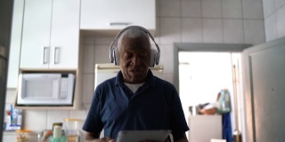 老人走路和听音乐的数字平板电脑在家
