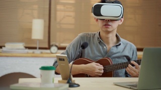 亚洲人使用VR耳机在家里在线教吉他视频素材模板下载