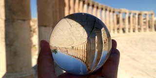 水晶球映着古罗马古城遗址、石柱、手拉手