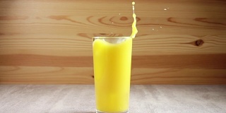 冰块滴入装有橙汁的玻璃杯中。慢动作
