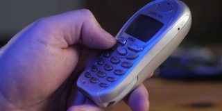 用手指在旧的、手机键盘上输入电话号码的特写