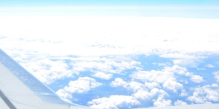 从飞机的窗口望出去，机翼上的飞机飞过云层，明亮的阳光在天空中刺眼。乘飞机旅行的飞机高清视频