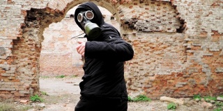 一个戴着防毒面具穿着黑色衣服的人跑在一座废弃的废墟上。跟踪者概念，核化学战争幸存者。缓慢的运动。