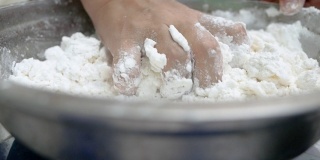 亚洲年轻女子正在做泰国饺子甜点或布阿洛伊糖果。将面粉和椰奶混合，揉成面团，做成布阿洛伊球的过程的特写。