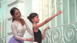 在泰国曼谷，一名亚洲青少年芭蕾舞者在当地街道上练习芭蕾舞，年轻的女芭蕾舞教师。概念活泼的年轻妇女和孩子在周末的活动。视频素材模板下载