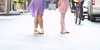 一个阳光明媚的日子里，在泰国曼谷的街道上，一名亚洲芭蕾舞少年正在练习芭蕾舞，动作就像年轻女芭蕾舞教师的动作一样。概念活泼的年轻妇女和孩子在周末的活动。