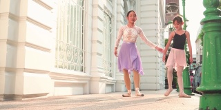 在泰国一个阳光明媚的日子里，一名亚洲青少年芭蕾舞者在曼谷的街道上练习芭蕾舞，动作和当芭蕾舞老师的年轻女子一样。概念活泼的年轻妇女和孩子在周末的活动。