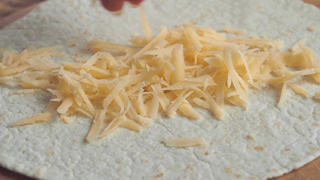 磨碎的奶酪浇在皮塔饼上。烹饪披萨油炸玉米粉饼。近距离