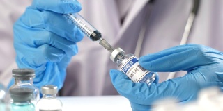 医生用注射器从药瓶中取出正在接受COVID-19疫苗接种的患者，在实验室用注射器注射疫苗