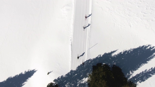 在一个阳光明媚的冬日，科罗拉多州，一组四名成年人在雪道上越野滑雪