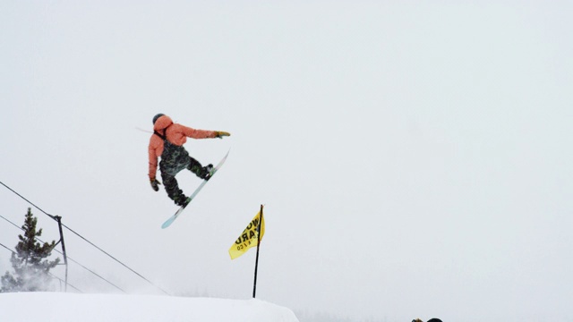 完整的冬季装备滑雪板完成一个“前侧360尾巴抓取”在博尔德附近的埃尔多拉滑雪度假村跳跃的技巧，科罗拉多州在一个下雪的，阴天
