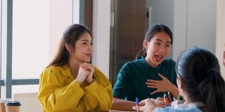 亚洲用户体验开发人员和ui设计师一起谈论放松前会议关于移动应用界面线框在现代办公室。创意数字发展机构