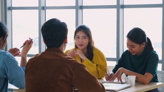 亚洲用户体验开发人员和ui设计师一起谈论放松前会议关于移动应用界面线框在现代办公室。创意数字发展机构视频素材模板下载