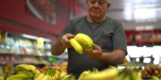 一位老人在超市里挑选香蕉