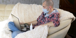 一名男子戴着防护面具坐在沙发上，通过视频链接向医生咨询如何治疗这种疾病。