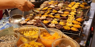 异国情调的东方美味甜点，不同寻常的色彩斑斓的传统菜肴在柜台上的集市与街头小吃。曼谷的晚间美食广场，烹饪之都。夜市。