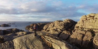 一名女性户外探险的无人机镜头:在挪威徒步旅行，在峡湾边的山上