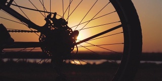自行车车轮和女脚鞋在春天的晚上骑在城外照顾环境在日落慢动作
