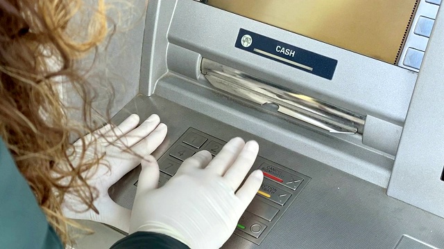 女性用手在ATM键盘上输入PIN码。