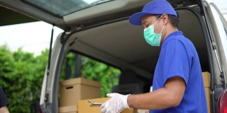 冠状病毒的概念。亚洲蓝色快递员戴着防护口罩和医用橡胶手套在发货前将包裹寄给客户。4k分辨率和慢动作拍摄。