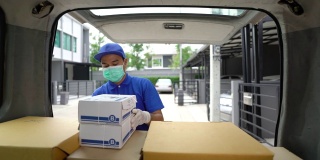 冠状病毒的概念。蓝色快递英俊的亚洲男子戴着防护面具和医用橡胶手套把纸箱放在汽车后备箱。在疫情中做志愿者工作。4 k决议。