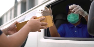 冠状病毒的概念。亚洲蓝色快递员戴着防护面具和医用橡胶手套在货车上给客户送包裹。4k分辨率和慢动作拍摄。