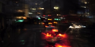 在雨天，从公共汽车窗口散焦的前灯和城市灯光