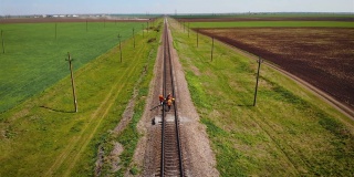 三名铁路工人在轨道上搬运手推车的鸟瞰图，以探索轨道和防止事故发生