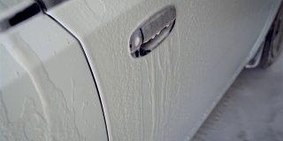 汽车上覆盖着白色的洗涤泡沫。汽车清洗服务