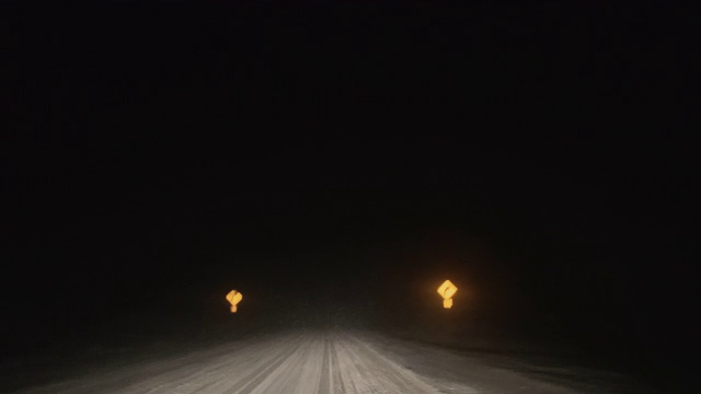 在暴风雪的夜晚沿着道路行驶，同时交替使用远光灯和远光灯(前灯)