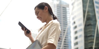 亚洲女商人在步行上班时使用智能手机