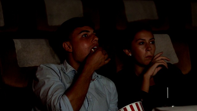 一对年轻夫妇在电影院幸福地看电影