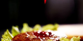 用厨房慢动作将番茄酱倒在汉堡上
