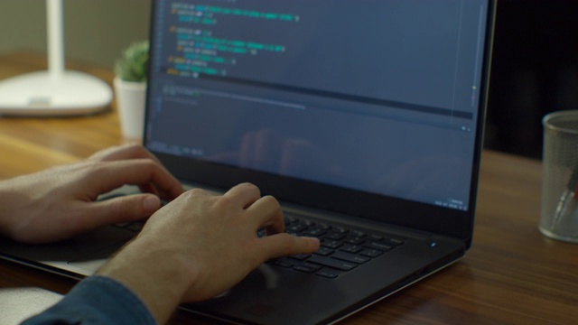 近手工程师开发软件应用程序，使用数字笔记本电脑在屏幕上输入代码，程序员编码互联网安全系统，在办公室设计人工智能项目。