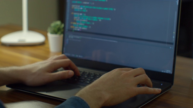 近手工程师开发软件应用程序，使用数字笔记本电脑在屏幕上输入代码，程序员编码互联网安全系统，在办公室设计人工智能项目。