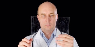 光头医生在透明平板电脑屏幕上滑动黑色背景。男医生在医疗袍滑动触摸屏在未来的平板电脑隔离在工作室。