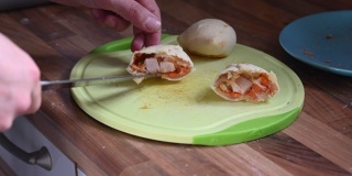刚从烤箱里取出的热气腾腾的饺子被放在砧板上分割，里面用锋利的刀显示