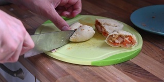 刚从烤箱里取出的热气腾腾的饺子被切在砧板上，里面是用锋利的刀缓慢移动的