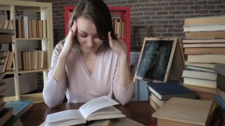 学生读的书。在一大堆书中，这个女人读教科书。考试准备。视频素材模板下载