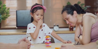 三代快乐的亚洲家庭在家里的客厅玩棋盘游戏