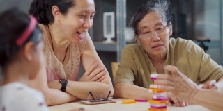 三代快乐的亚洲家庭在家里的客厅玩棋盘游戏