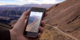 在阿根廷高原地区Jujuy省的Lipan Slope，男性用旧智能手机拍照。