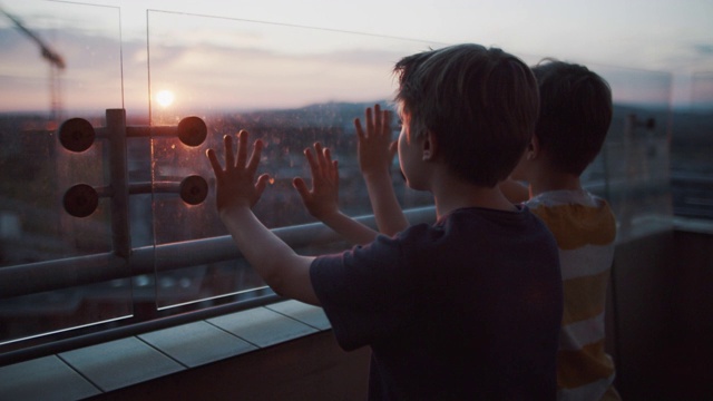 两个孩子在阳台上看日落