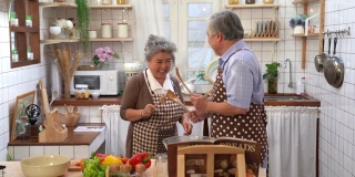 资深亚洲情侣在厨房里一起快乐做饭，退休后幸福生活。