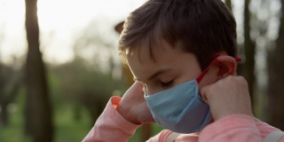 一个戴着医用口罩的人站在户外。少年摘下面具