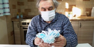 防病毒保护。新型冠状病毒肺炎那位戴着医用防护面罩的老人正坐在厨房的一张桌子旁。
