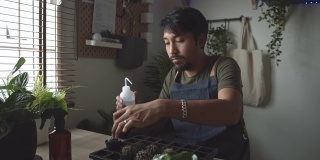 时髦的亚洲男人在家给室内植物浇水