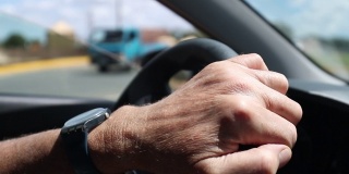 老人手握方向盘在路上开车
