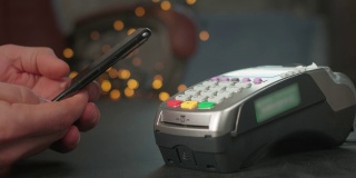 使用非接触式POS支付终端进行电话支付。用户在商店或餐厅使用智能手机购物。无现金钱包中的电子货币